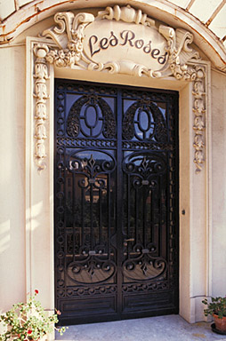 Détail : l'encadrement sculpté ainsi que la ferronnerie de la porte d'entrée sur la façade ouest, depuis l'ouest.