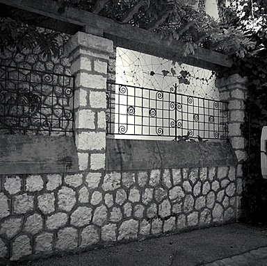Mur de clôture. Vue partielle avec sa pergola et se grilles.