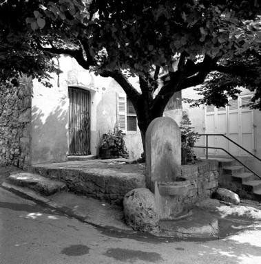 Maison avec terrasse en pierre et fontaine.