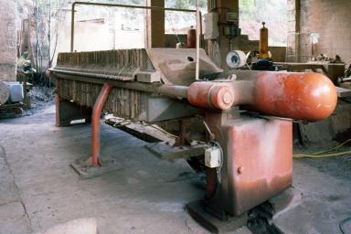 Aire de lavage de la terre. Extérieur sous appentis. "Filtre presse". Machine qui reçoit la barbotine et la conditionne en galette.