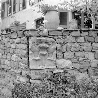 Jardin : chapitreau antique remployé dans un mur de soutènement.