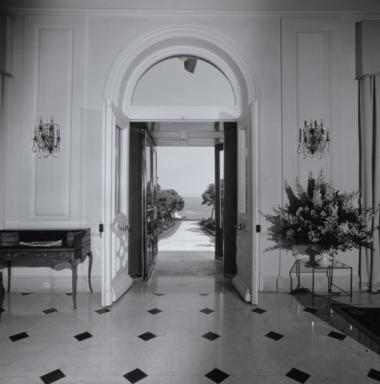L'allée située dans l'axe de la façade ouest vue depuis l'intérieur du vestibule, ave lac porte d'entrée ouverte au premier plan.