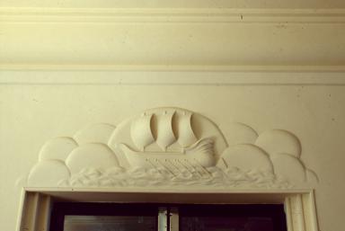 Vue de détail du bas-relief situé au-dessus de la porte de la salle à manger, depuis le vestibule.