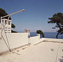 La maison. La terrasse de couverture. Souches de cheminées du côté nord et potence métallique.