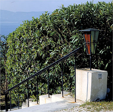 Détail de la rampe en fer-forgé et d'une lanterne située sur l'escalier dans le jardin.
