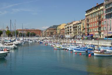 Collection de pointus traditionnels regroupés dans le Bassin Lympia du port de Nice ; église Notre-Dame du port en arrière-plan à gauche.