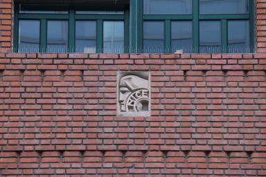 Détail de sculpture rapportée en pierre et calepin de parements en brique