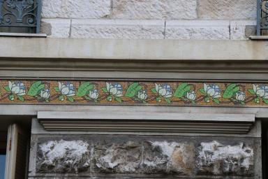 Détail rapproché sur un frise en céramique sur le bandeau intermédiaire