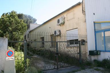 Vue sur le mur est l'ex-ferronnerie percé d'ouverture pour les ateliers ou bureaux. En arrière plan collé à l'ex-ferronnerie un logement typique à toiture plate.