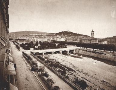 Square Massna et quai Saint-Jean-Baptiste vus depuis le sud-ouest, Nice [circa 1870]. La photographie montre le quai Saint-Jean-Baptiste ralign et la premire partie du fleuve couverte pour accueillir un square. La photographie est prise depuis l'actuel Htel Aston en direction de l'est.  ; Square Massna et quai Saint-Jean-Baptiste vus depuis le sud-ouest, Nice [circa 1870].