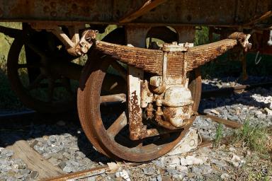 Wagon plateforme ex-PLM : gros plan sur une boite d'essieu et la suspension à lames