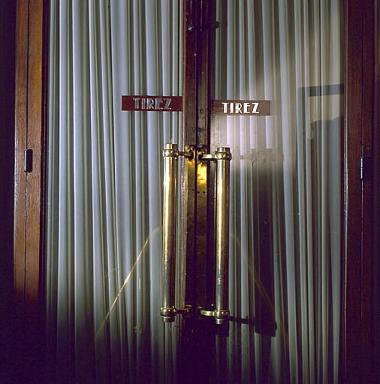 Portes vitrées du salon rouge, poignées et typographie.