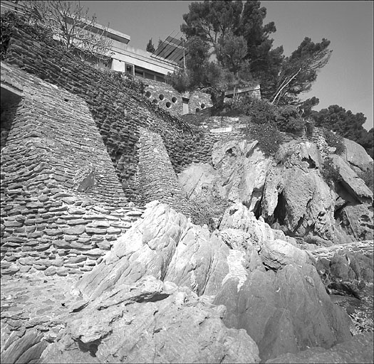 Vue d'ensemble du mur de soutnement du jardin avec la faade sud  l'arrire plan, depuis le bord de mer.