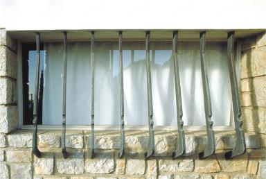 Vue de détail d'une grille en fer-forgé située à l'étage, sur la façade sud.