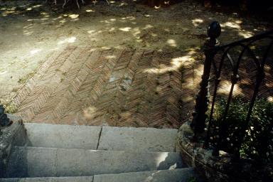 Cour avec pavement en briques en arête-de-poisson; départ de l'escalier de la terrasse.