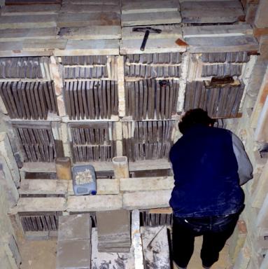 Vue intrieure de la chambre du four industriel  bois. Matriel d'enfournement. Pose des manchons rfractaires. Encabanage des carreaux  l'aide de briques.