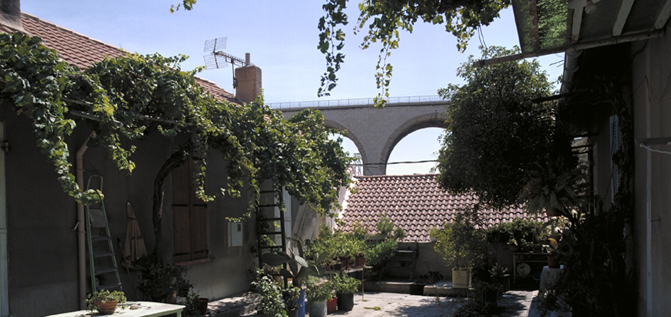 ;Marseille 16e arrondissement (Dép.13), Antoine-Castejon, Vue prise au centre de la cour-chemin, en direction du sud. De part et d'autre les barres parallèlles des logis. Au fond, la courée dite Maisons Mouraille est fermée par un muret surplombant la dénivellation du terrain.;